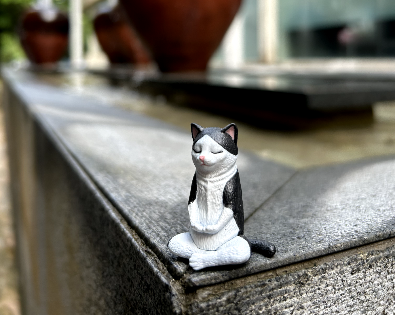 Cat figurine meditating on the edge of a concrete step